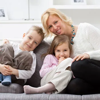 woman and two children siting on a couch smiling